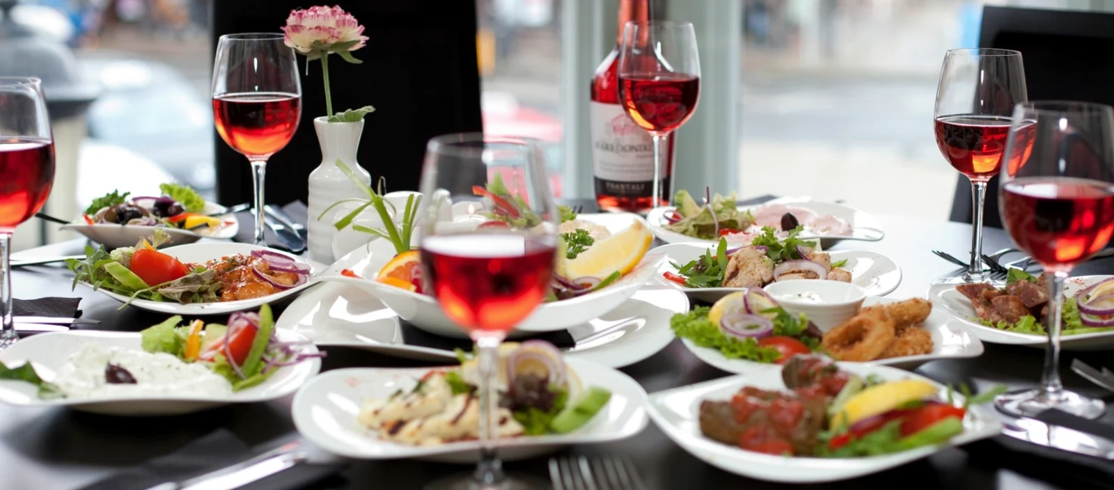 A table filled with El Greco sharing dishes and Greek wine